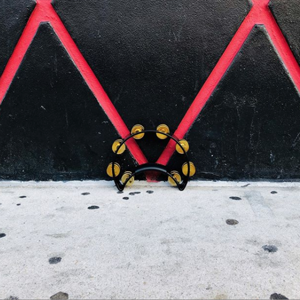 black crescent-shaped tambourine in front of black and red wall