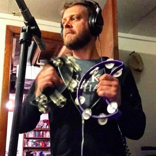 man wearing headphones using two crescent-shaped tambourines