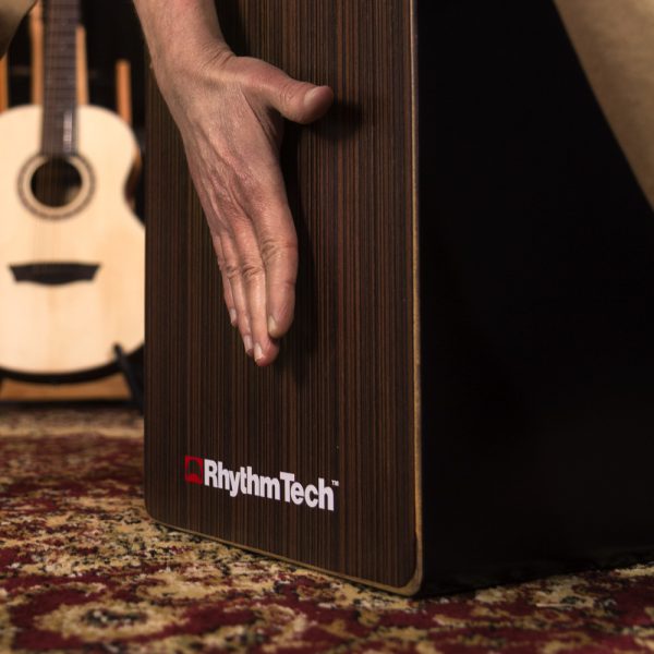 closeup of hand playing Rhythm Tech cajon in front of acoustic guitar