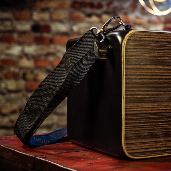 closeup of strap on Rhythm Tech Bongo Cajon on wooden table in front of brick wall