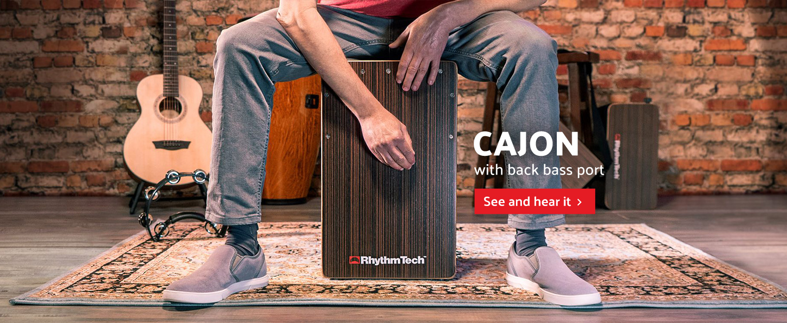 man playing Rythm Tech cajon in front of brick wall